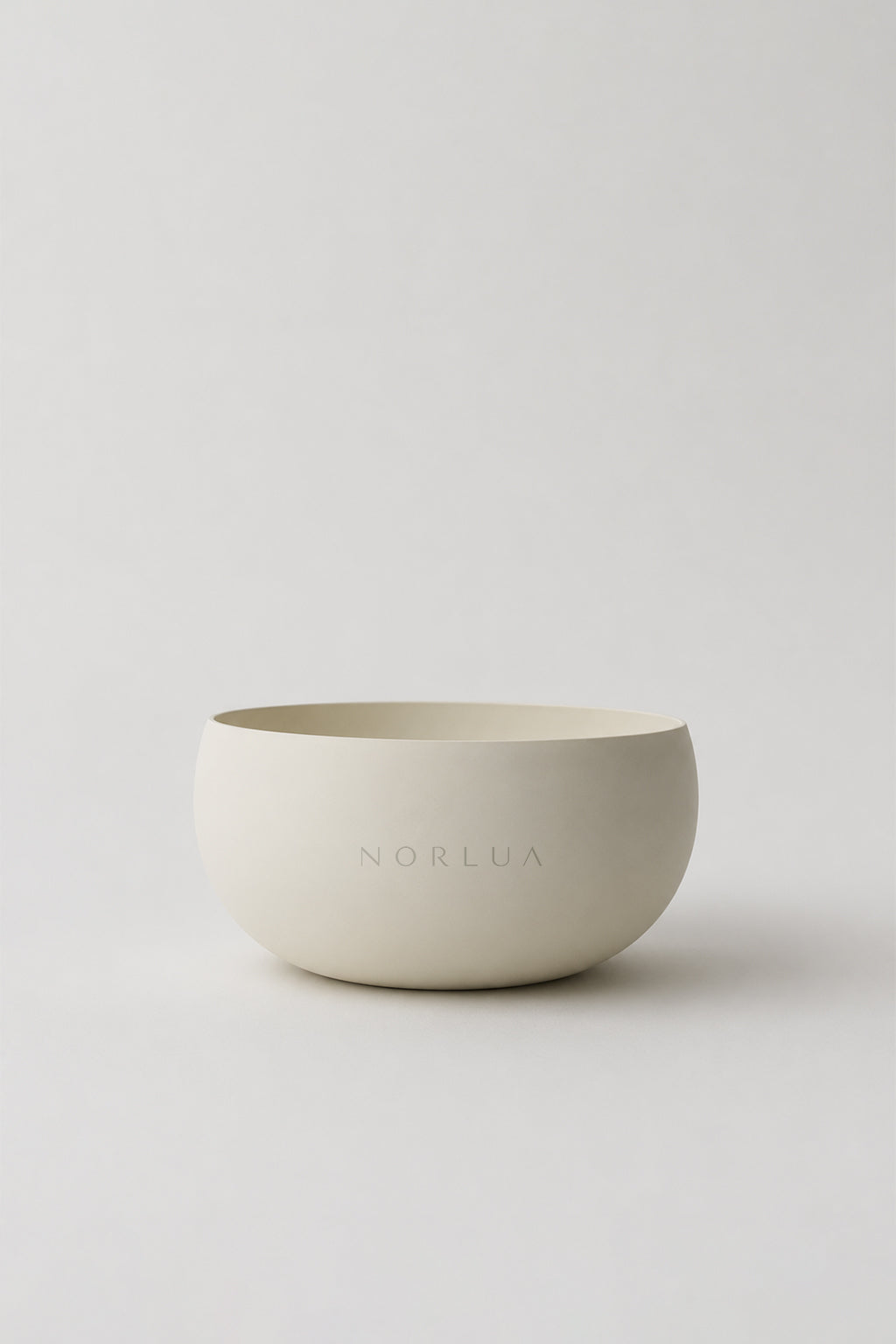 Front view of the NORLUA brass singing bowl in a warm white matte finish