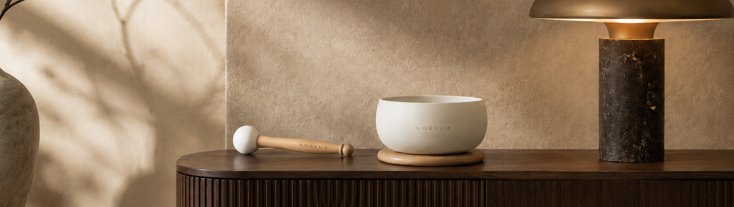 NORLUA singing bowl displayed on a wooden shelf in warm natural light